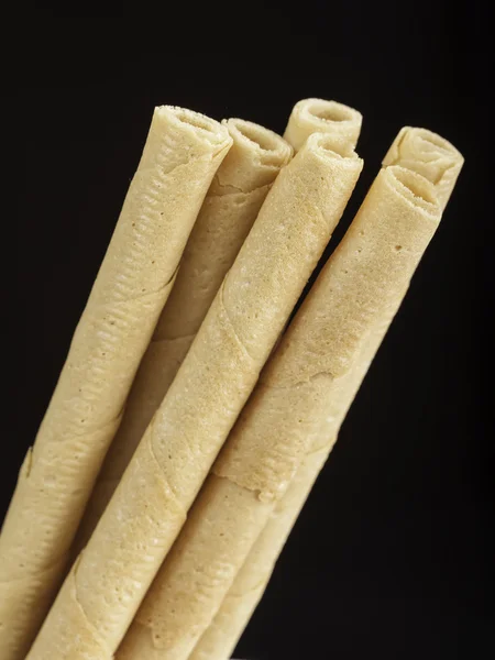 Rolled wafers on black background — Stock Photo, Image