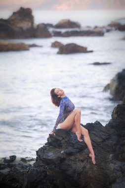 bir taş üzerinde oturan jimnastikçi kız