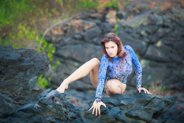 bir taş üzerinde oturan jimnastikçi kız