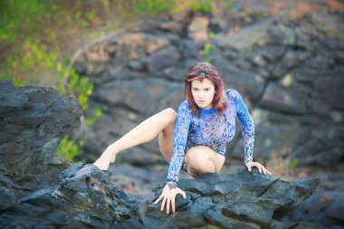 bir taş üzerinde oturan jimnastikçi kız