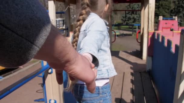 금발의 어린 여학생 이 의붓아버지의 손을 잡고 걷는다 — 비디오