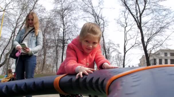 Deleitado colegiala juega en la atracción del parque infantil en el parque — Vídeos de Stock