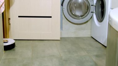 Robot elektrikli süpürge, banyo kapısı açık çamaşır makinesine gidiyor. Ev temizliği işi. Kolay işler için ev aletleri