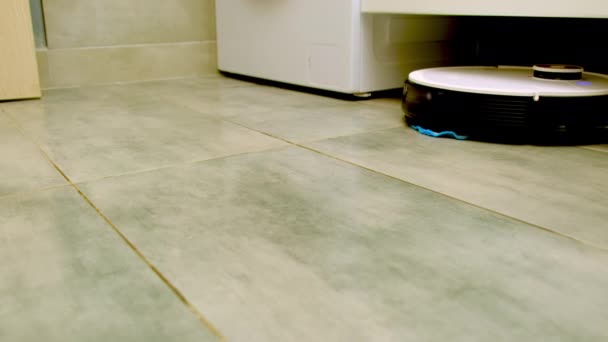 自動ロボット掃除機は浴室のキャビネットの下に乗る 毎日の家の掃除手順 家事容易化のための家電 — ストック動画