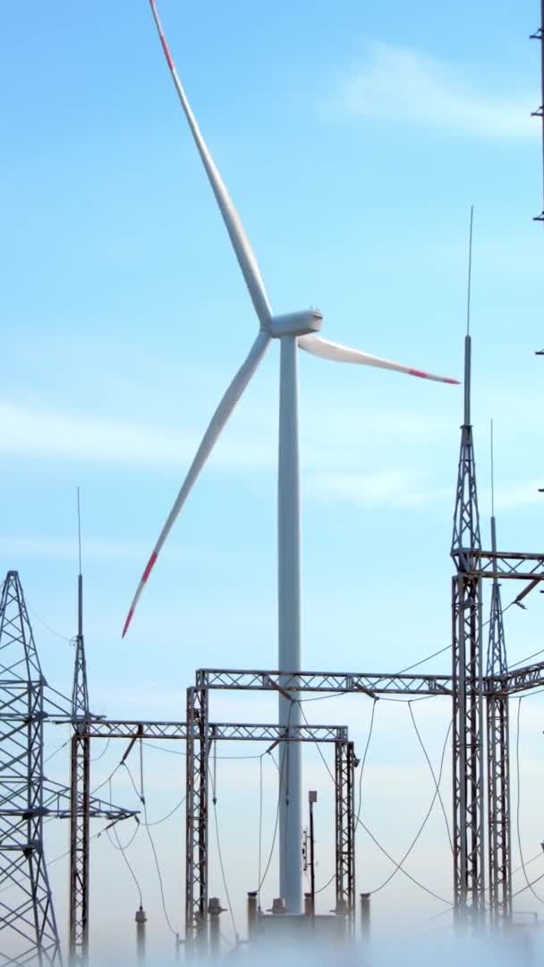 Windkraftanlage Und Stromübertragung Bahnhof Mächtige Windräder Produzieren Hinter Hohen Gittertürmen — Stockvideo