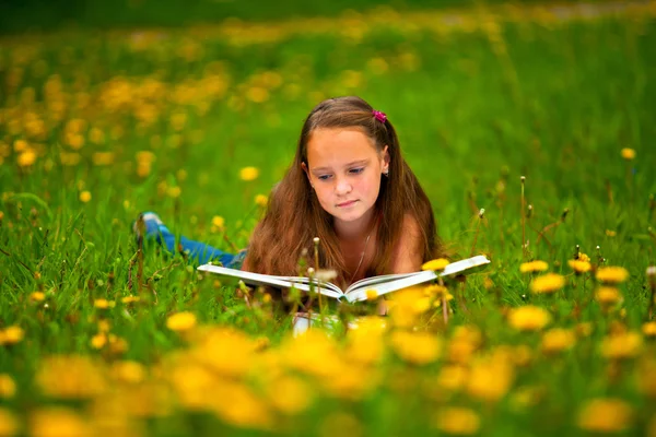 Kind lezen van een boek terwijl liggen in het gras — Stockfoto