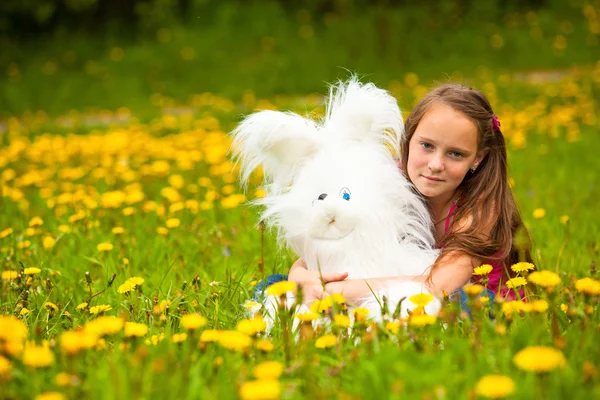 Маленькая девочка держит мягкую игрушку в парке, смотрит в камеру . — стоковое фото