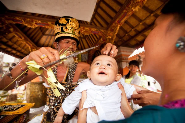 БАЛИ, ИНДОНЕЗИЯ - 28 МАРТА: Неопознанный ребенок во время церемоний в Отоне - это первая церемония, на которой младенцу разрешается прикасаться к земле 28 марта 2012 года на Бали, Индон — стоковое фото