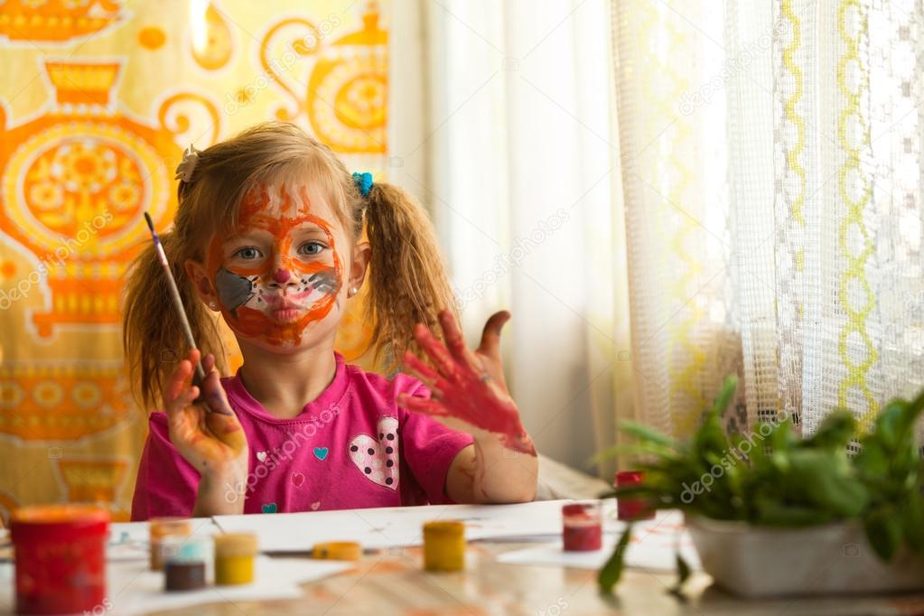 Beautiful little girl artist with paint of face.