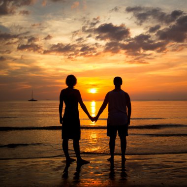 Genç çift ellerimi deniz sahilde günbatımı