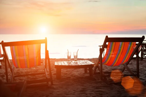 Espreguiçadeiras na praia ao pôr do sol — Fotografia de Stock