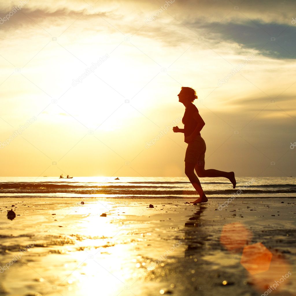 Silhouette of a young woman jogger at sunset on the seashore