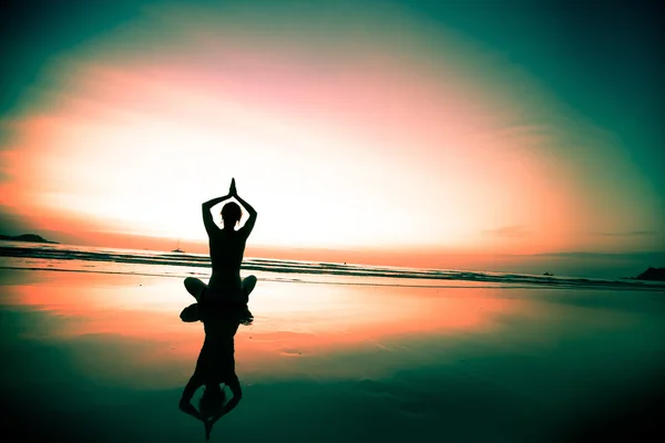 Femme méditant sur la plage au coucher du soleil — Photo