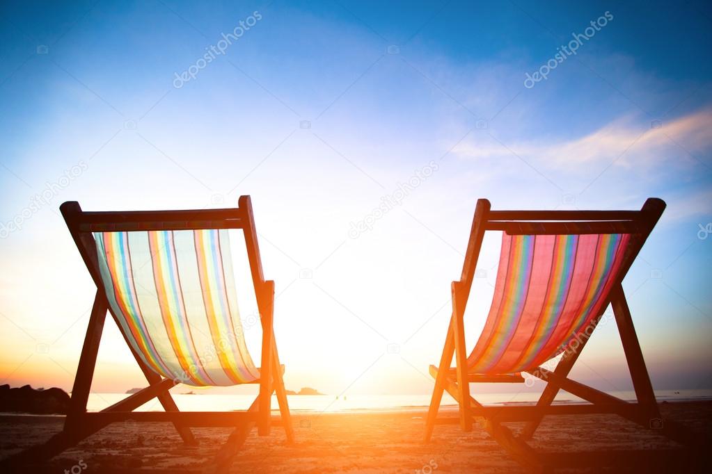 Pair of beach loungers on the deserted coast sea at sunrise, perfect vacation concept