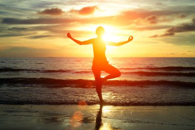pratik yoga, siam Körfezi sahilinde günbatımını sırasında genç bir kadın