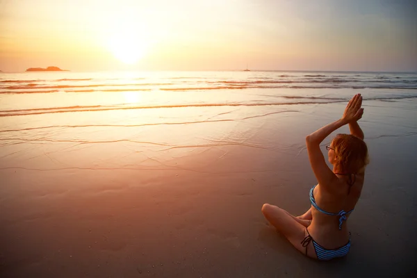Mulher meditando na praia ao pôr do sol. — Fotografia de Stock