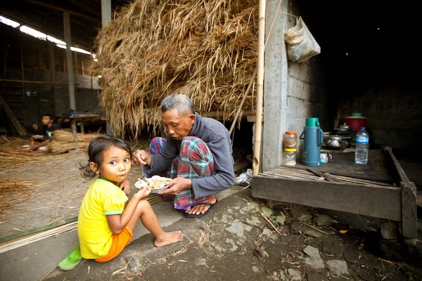 BALI - APRIL 3: Unidentified poor child eats with his father during a break working on the farm on April 3, 2012 on Bali. Daily caloric intake per capita in Indonesia is 2891 kcal per person. — Stock Photo, Image