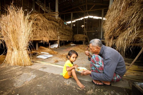БАЛИ - 3 апреля: Неопознанный бедный ребенок ест со своим отцом во время перерыва на ферме 3 апреля 2012 года на Бали. Ежедневное потребление калорий на душу населения в Индонезии составляет 2891 ккал на человека . — стоковое фото