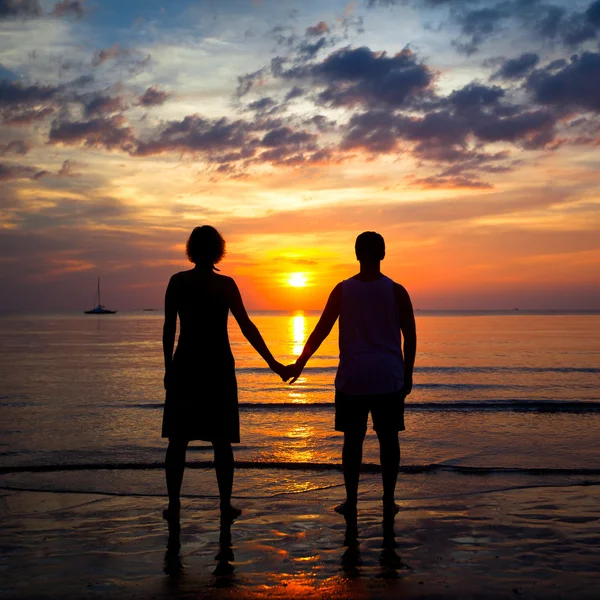 Silhouettes jeune couple sur la plage au coucher du soleil, photo romantique — Photo