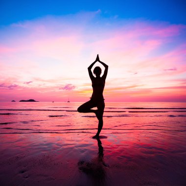 genç kadın yoga pratik günbatımında deniz kenarında