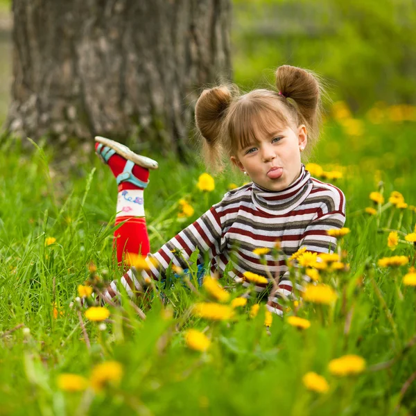 Милая эмоциональная пятилетняя девочка сидит в траве — стоковое фото