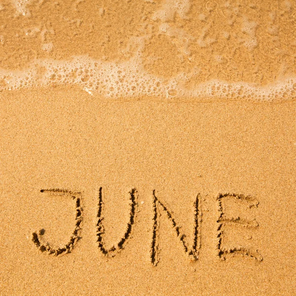 Junho - escrito em areia na textura da praia - onda suave do mar . — Fotografia de Stock
