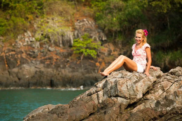 Siedzi blondynka na skałach nad morzem — Zdjęcie stockowe