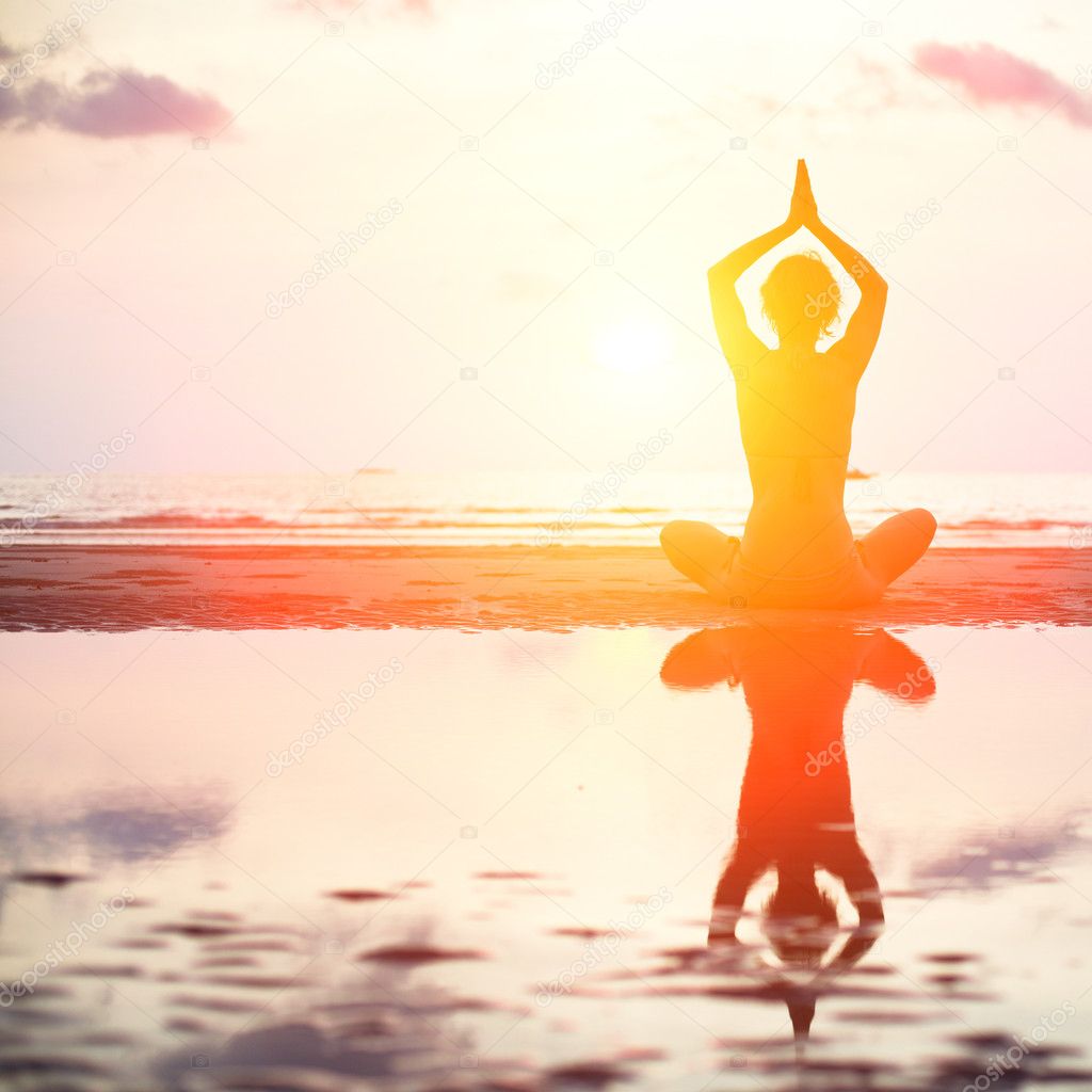 Yoga woman sitting in lotus pose on the beach during sunset.