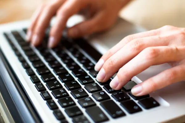 Hands typing text on a laptop keyboard — Stock Photo, Image