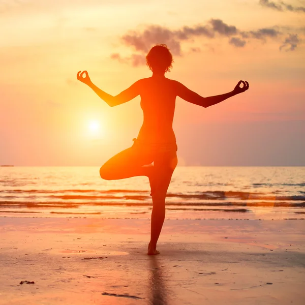 Sylwetka kobiety piękne jogi na plaży o zachodzie słońca. — Zdjęcie stockowe