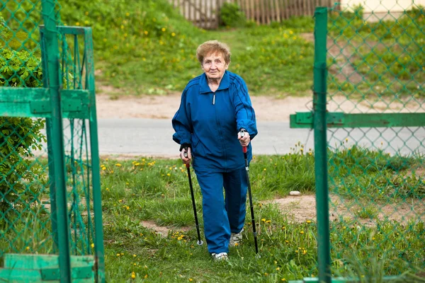 Actieve oude vrouw nordic walking buitenshuis, 85 jaar oud. — Stockfoto