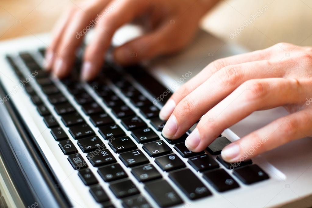 Hands typing text on a laptop keyboard