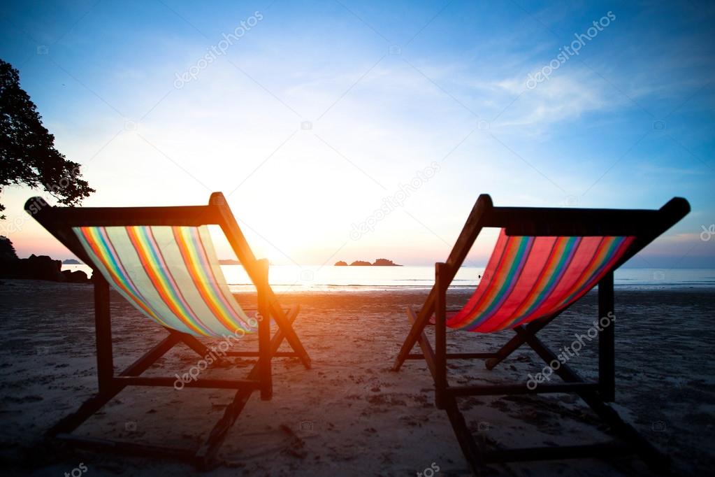 Beach loungers on the deserted coast sea at sunrise.