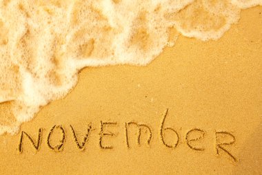 November - written in sand on beach texture