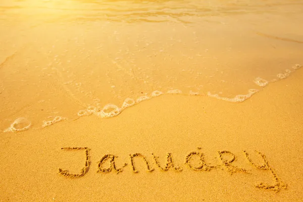 Januari - geschreven in het zand op het strand textuur — Stockfoto