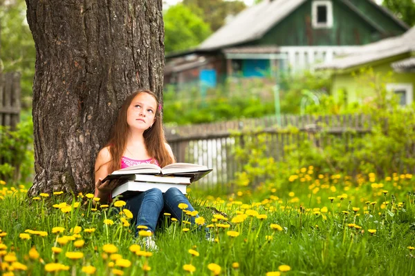 Een meisje, 11 jaar oud, leest een boek in de weide — Stockfoto