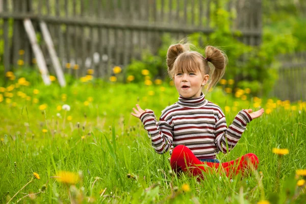 Schönes emotionales fünfjähriges Mädchen, das im Gras sitzt. — Stockfoto