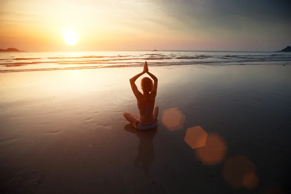 Donna di yoga seduta sulla costa del mare al tramonto — Foto Stock