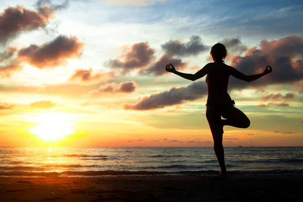Young woman practicing yoga on the beach during the sunset — Stock Photo, Image