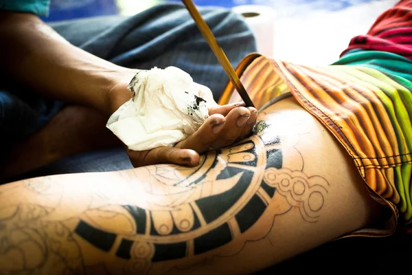 CAMBIO, TAILANDIA - DIC 24: Maestro no identificado hace bambú tradicional tatuaje, Dic 24, 2012 en Chang, Tailandia. Los tatuadores tailandeses son muy populares entre los turistas, los precios van desde 500 thai baht y hasta — Foto de Stock