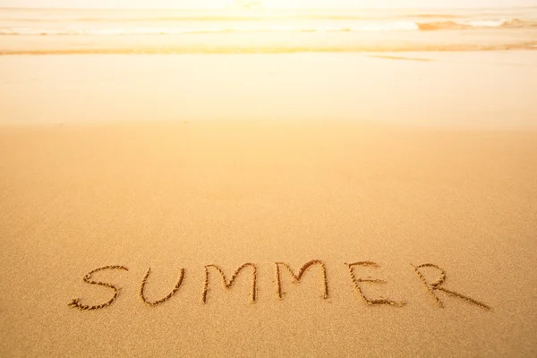 Καλοκαίρι - κείμενο γραμμένο με το χέρι στην άμμο σε μια παραλία, με ένα απαλό κύμα. — Φωτογραφία Αρχείου