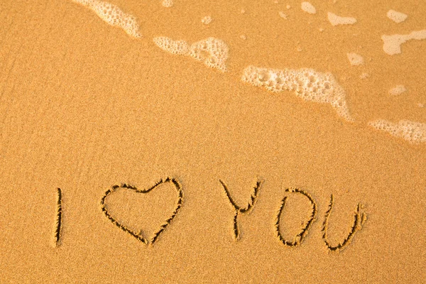 Ich liebe dich - von Hand in Sand am Strand geschrieben, mit einer sanften Welle — Stockfoto