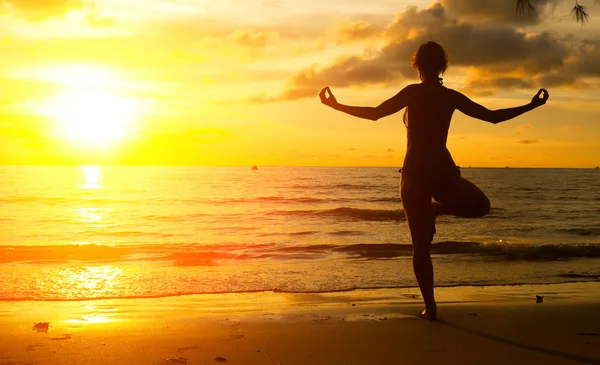 Jeune femme pratiquant le yoga en bord de mer en Thaïlande au coucher du soleil . — Photo