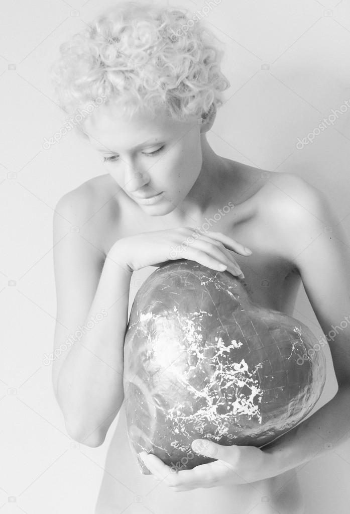 Young sexy girl holding a big toy heart, black and white photo (studio)