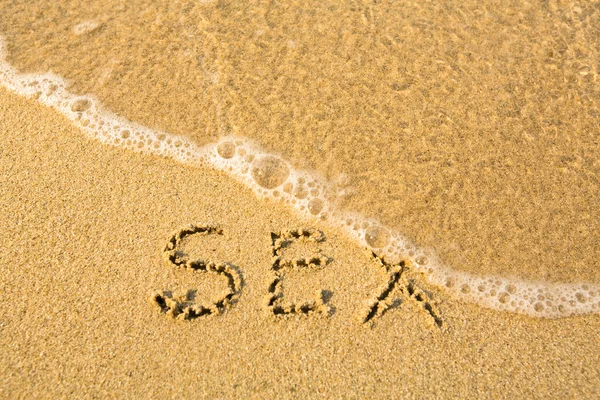 Geslacht - geschreven in het zand op het strand textuur - zachte Golf van de zee — Stockfoto
