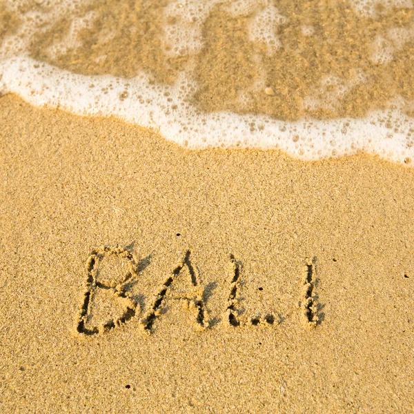 Bali - napisał w piasku na plaży tekstury - miękkich fal morza. — Zdjęcie stockowe