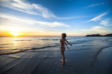 deniz kıyısı üzerinde duran genç kadın