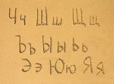 bir kum plajı üzerinde yazılı Rus alfabesi