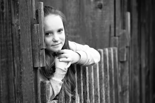 Adolescente debout près d'une clôture rurale vintage, photo noir et blanc . — Photo