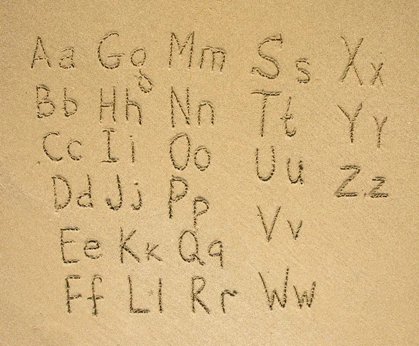O alfabeto escrito numa praia de areia — Fotografia de Stock